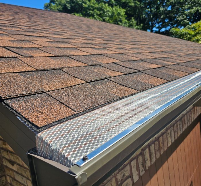 Klean gutter on a roof with a blue sky and trees in background